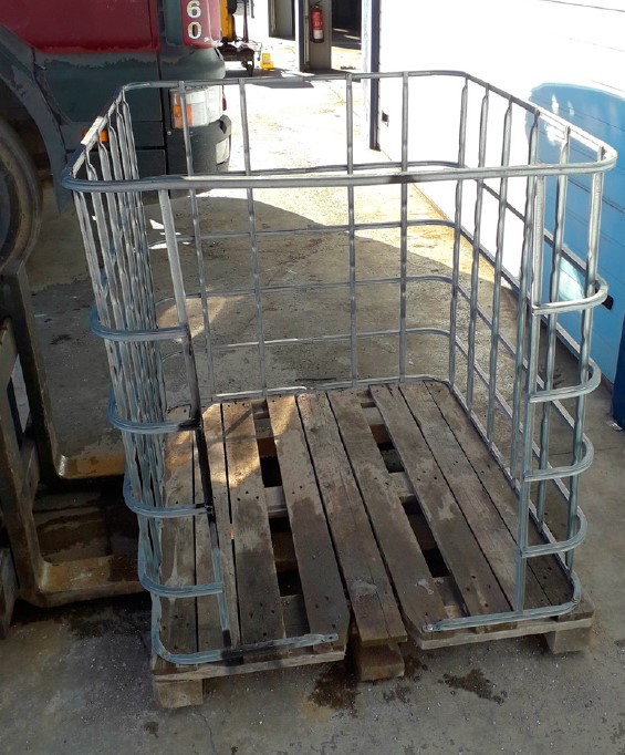 Cesta de fabricación casera, conformada a partir de la estructura del depósito. Cesta apoyada sobre las horquillas de la carretilla por el lado más largo del palé. Lateral de la cesta abierto