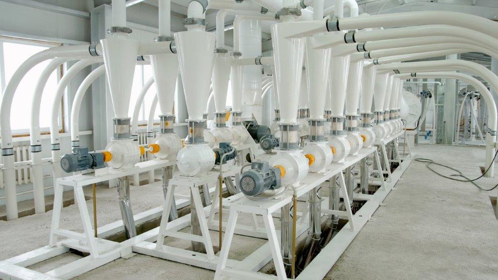 En la imagen se observa una batería de molinos eléctricos para moler grano de trigo dentro del proceso de producción de harina