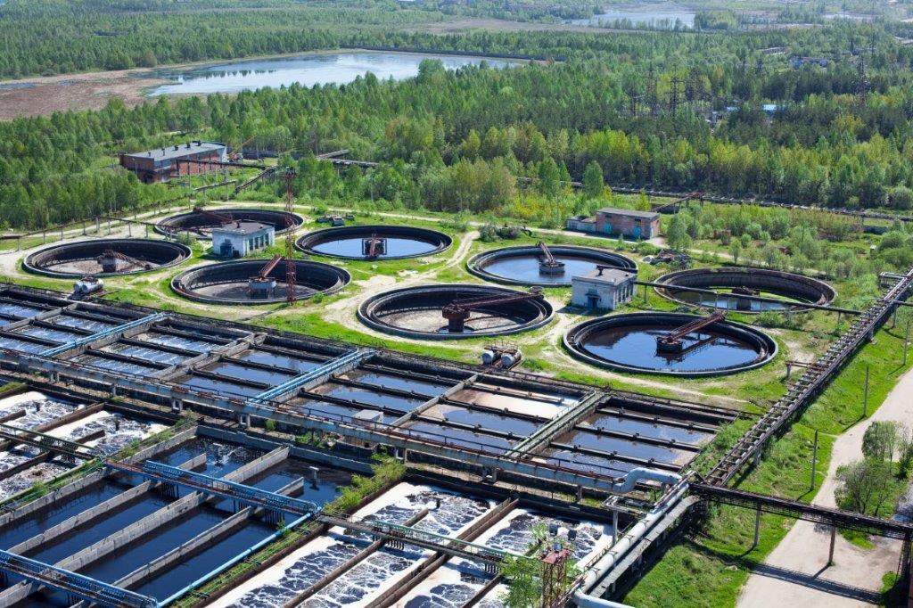 En la imagen se observa una estación de tratamiento de aguas con tanques de agua de reciclaje al fondo.