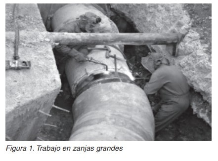 Dos trabajadores en una zanja grande montando una conducción de gran diámetro.
