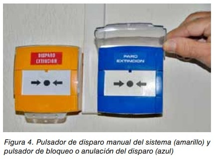 Pulsador amarillo de disparo manual de extinción y pulsador azul de bloqueo o anulación del disparo en una pared.