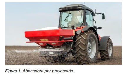 Tractor agrícola con abonadora por proyección distribuyendo fertilizante en un campo.
