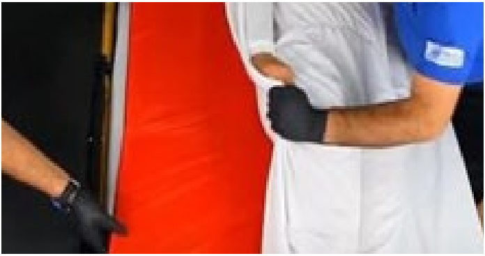 Operarios con guantes manipulando una lámina de material rojo sobre superficie blanca.
